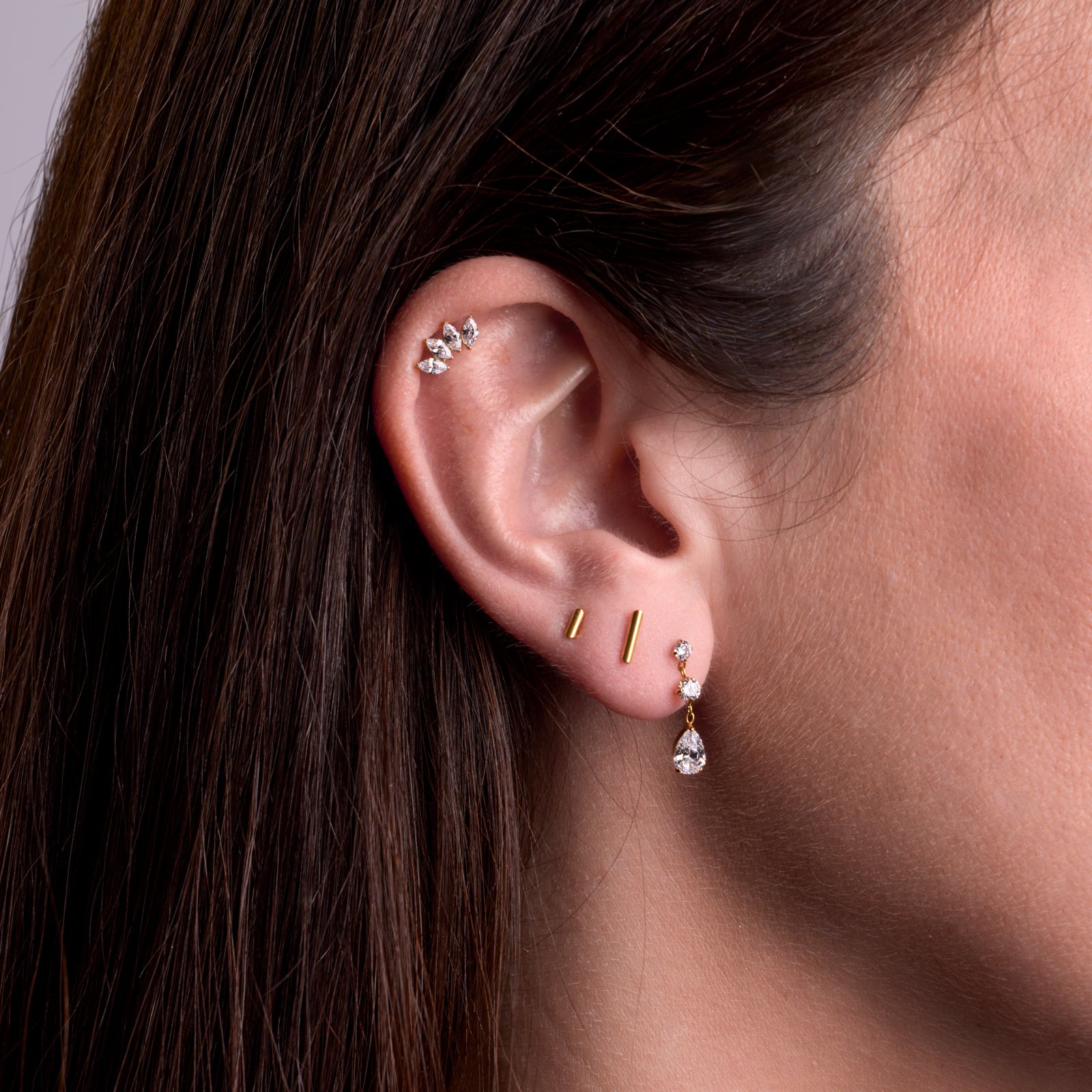 Bijoux de piercing en titane à l'oreille: Sadira gold à l'hélix, lingot 4mm au deuxième lobe et lingot 7mm au 2ème lobe, Lungo blanc au premier lobe.